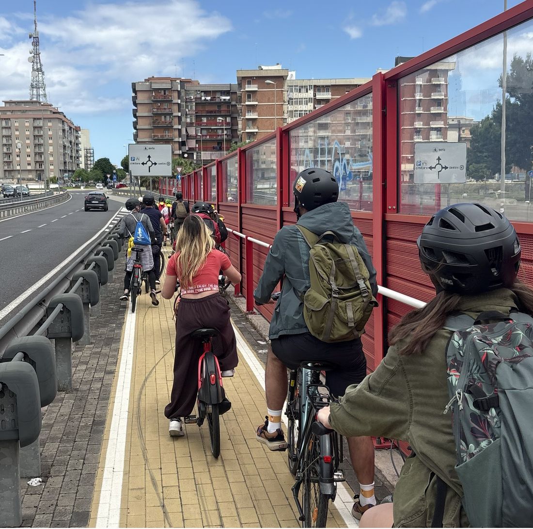Un gruppo di persone pedala in fila su una pista ciclabile urbana a Bari