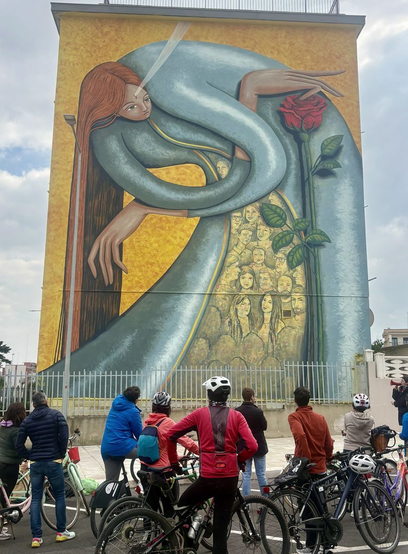 Ciclisti fermi davanti a un grande murale durante una pedalata di Terreno